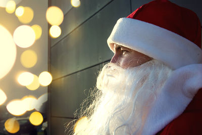 Close-up of santa wearing hat standing by wall