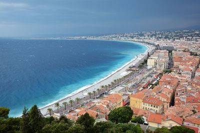 High angle view of townscape by sea against blue sky