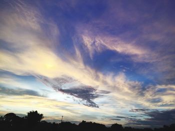 Low angle view of silhouette trees against dramatic sky