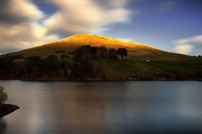 Scenic view of lake by mountain against sky