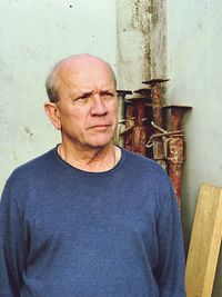 Thoughtful mature man standing by wall