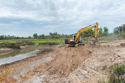 Construction site by dirt road against sky