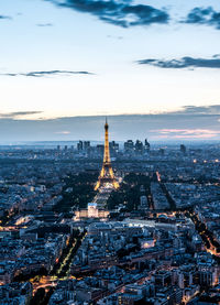 Aerial view of illuminated cityscape against cloudy sky