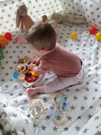 High angle view of baby girl playing with toy on bed at home