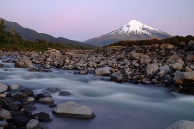 Stream flowing against mountain during winter