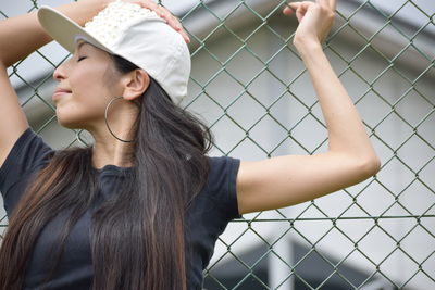 Hip-hop dancer wearing cap against fence