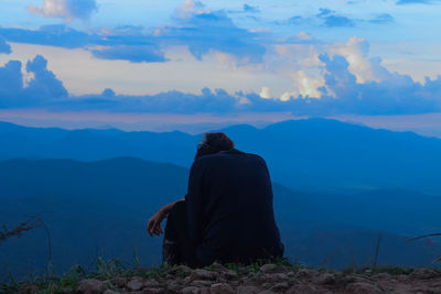 Rear view of man looking at mountains against sky