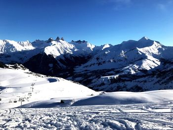 Scenic view of snowcapped mountains against clear blue sky