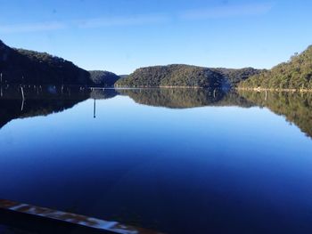 Scenic view of lake and mountains against clear blue sky