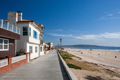 Footpath by sea and buildings against sky