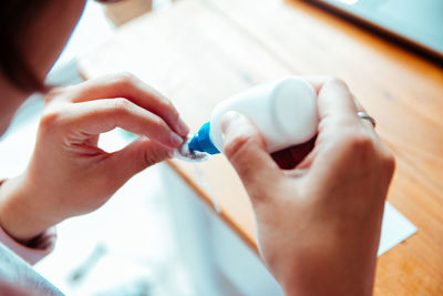 Close-up high angle view of woman holding glue bottle