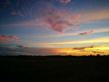 Scenic view of silhouette field against orange sky