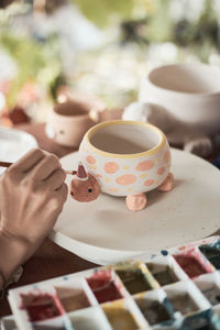 Cropped hand of woman holding coffee on table