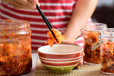 Close-up of hand holding glass jar on table