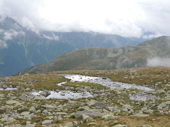 Scenic view of rocky mountains against cloudy sky during foggy weather