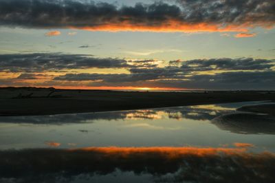 Scenic view of sea against cloudy sky at sunset