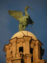 Low angle view of angel statue against blue sky