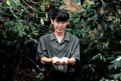 Portrait of young man standing against plants