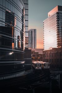 Trains on railroad tracks amidst buildings in city