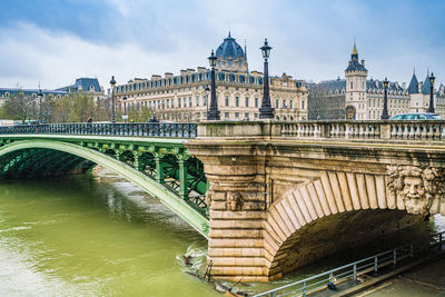 Arch bridge over river against sky in city