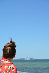 Woman looking at sunshine skyway bridge over tampa bay against clear blue sky