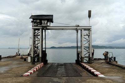 Pier on sea against cloudy sky