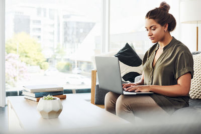 Young woman using mobile phone while sitting on sofa