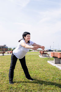 Full length of young man standing on field against sky