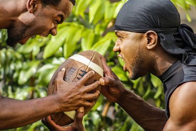 Side view of young rugby players tackling