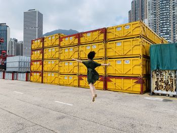 Full length rear view of woman walking against yellow buildings in city