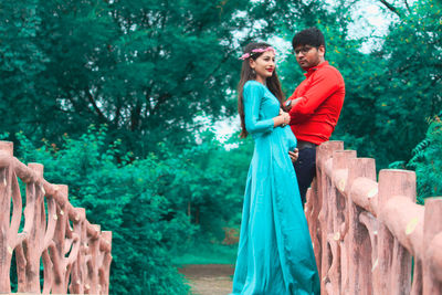 Pregnant young woman standing with man against trees