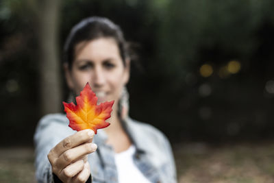 Portrait of woman holding leaf during autumn
