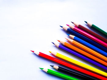 High angle view of colored pencils against white background