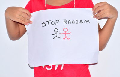 Midsection of woman holding paper while standing against white background