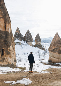 Rear view of man standing on snowcapped mountain