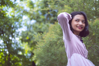 Close-up of smiling girl sitting against tree outdoors