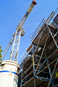 Low angle view of crane against clear blue sky