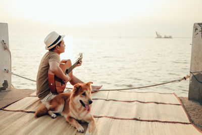 Man with dog sitting against the sky