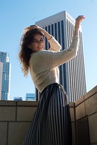 Side view of young woman standing against wall