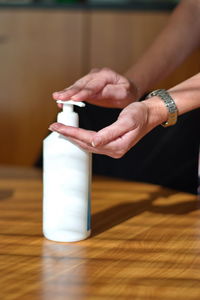 Close-up of woman hand holding bottle on table