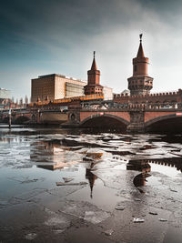 Arch bridge over river against buildings in city