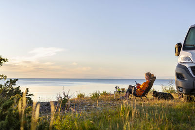 Woman relaxing on lounge chair at sea