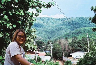 Portrait of smiling young woman against trees