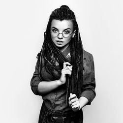 Portrait of young woman standing against white background