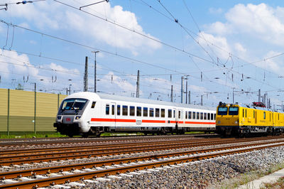 Modern train by cables against sky