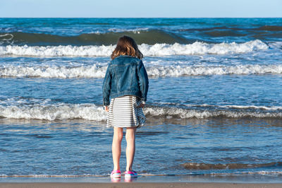 Rear view of cute girl standing on beach