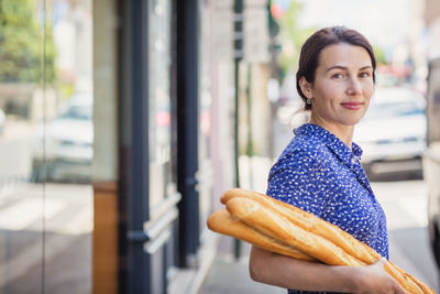 Young woman buying a french baguette