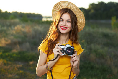Portrait of smiling young woman wearing hat standing outdoors
