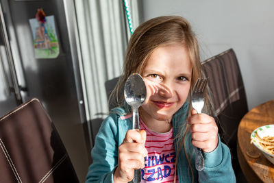 Portrait of happy girl holding camera at home