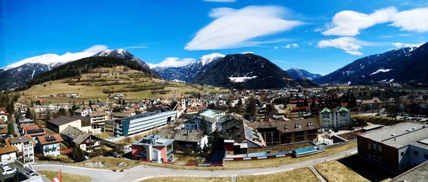 Aerial view of townscape by mountains against sky